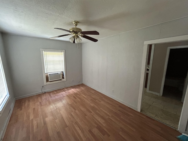 spare room with wood-type flooring, a textured ceiling, cooling unit, and ceiling fan