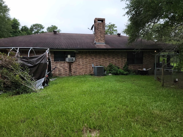 rear view of property with central AC unit, cooling unit, and a lawn