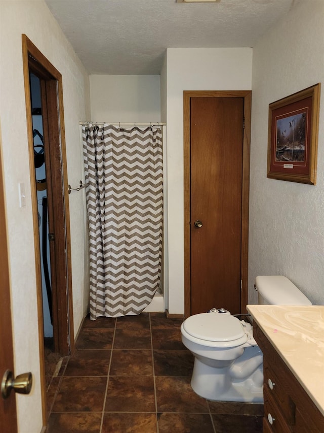 bathroom with a shower with curtain, vanity, a textured ceiling, and toilet