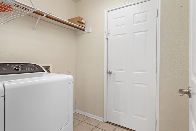 clothes washing area with washer / dryer and light tile patterned floors