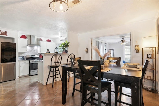 dining room featuring dark tile patterned flooring, ceiling fan, ornamental molding, and a textured ceiling