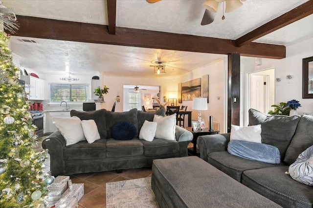 living room featuring light tile patterned floors, a textured ceiling, beam ceiling, and sink