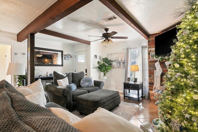 living room featuring ceiling fan, beamed ceiling, light tile patterned flooring, and a textured ceiling