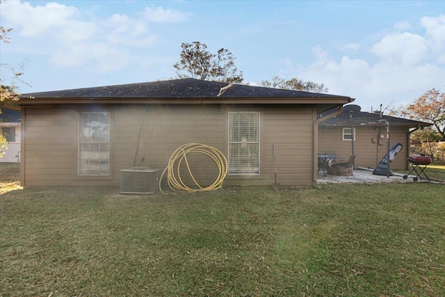 rear view of house with cooling unit, a patio area, and a yard