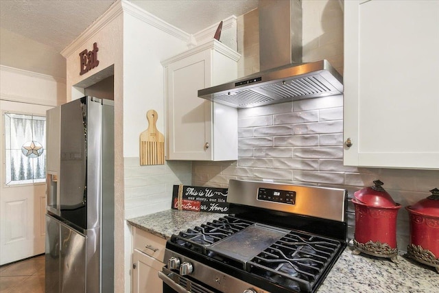 kitchen featuring stainless steel appliances, white cabinetry, and wall chimney range hood