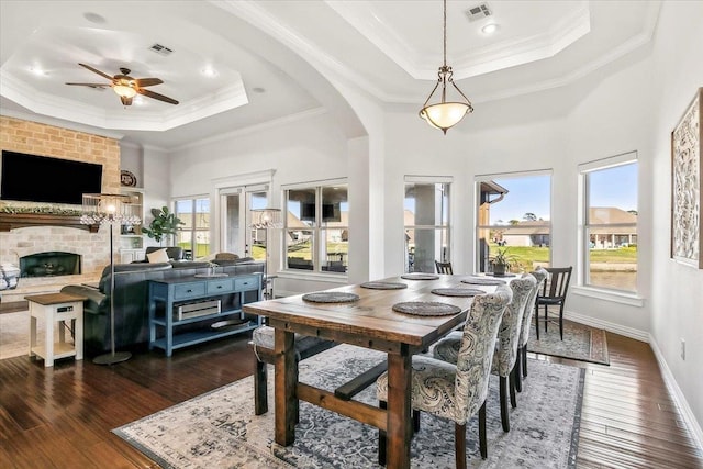 dining area with a tray ceiling, ceiling fan, a fireplace, and ornamental molding