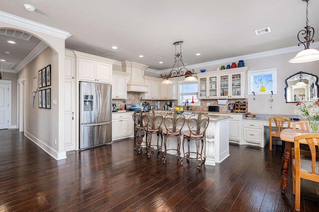 kitchen featuring visible vents, dark wood-style floors, custom range hood, glass insert cabinets, and appliances with stainless steel finishes