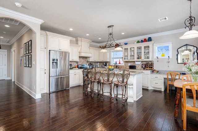 kitchen featuring dark wood-type flooring, visible vents, appliances with stainless steel finishes, custom exhaust hood, and glass insert cabinets