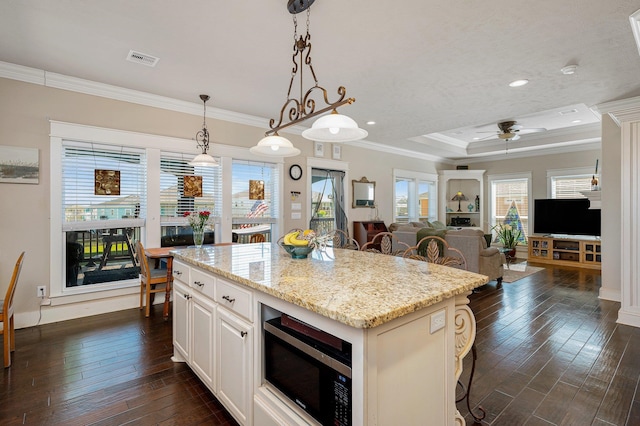 kitchen with ornamental molding, stainless steel microwave, dark wood finished floors, and visible vents