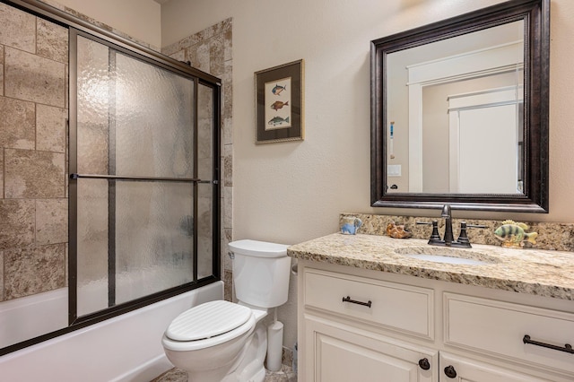 bathroom featuring toilet, combined bath / shower with glass door, and vanity