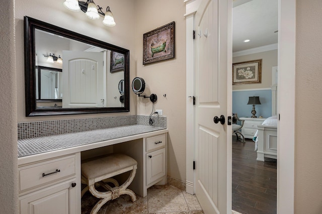 bathroom with tasteful backsplash, baseboards, ornamental molding, wood finished floors, and vanity