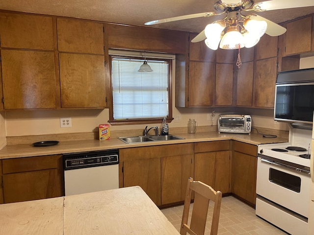 kitchen with pendant lighting, white appliances, ceiling fan, and sink