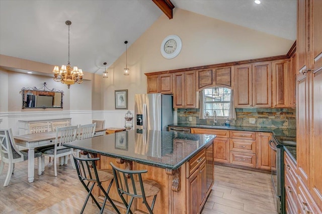 kitchen featuring a kitchen island, beamed ceiling, decorative backsplash, stainless steel appliances, and light hardwood / wood-style flooring