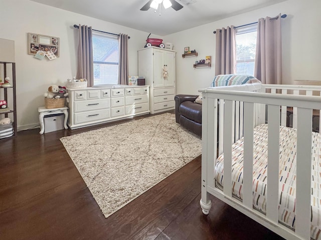 bedroom with a crib, dark hardwood / wood-style floors, and multiple windows