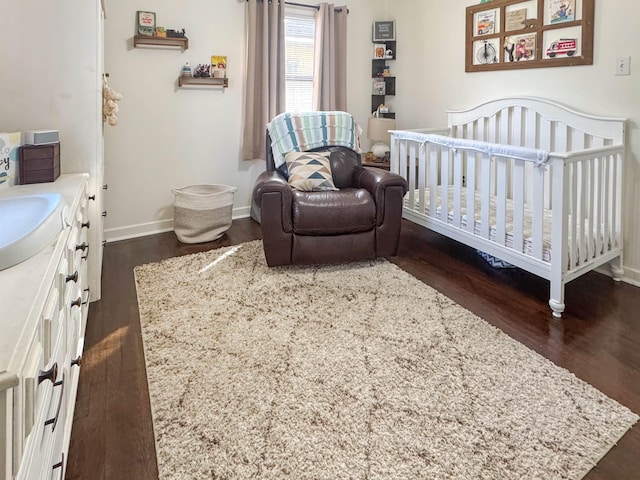 bedroom with dark hardwood / wood-style floors and a nursery area