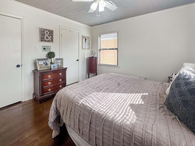 bedroom with dark hardwood / wood-style flooring, ornamental molding, and ceiling fan