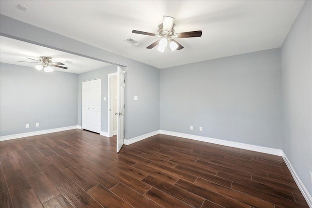 spare room featuring visible vents, ceiling fan, baseboards, and dark wood-style flooring