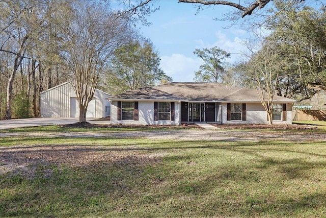 ranch-style house featuring a front yard, a garage, an outbuilding, and brick siding