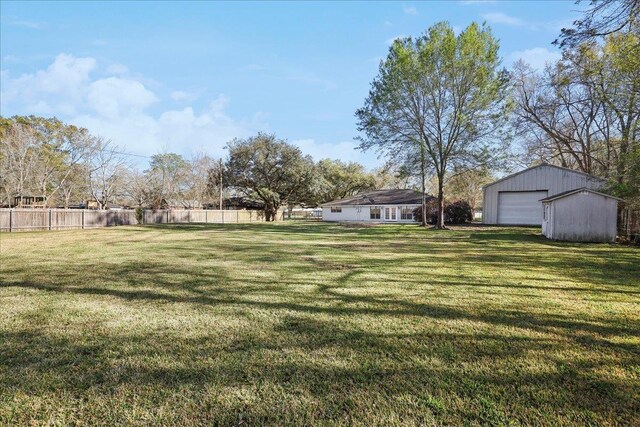 view of yard featuring a garage, an outdoor structure, and fence