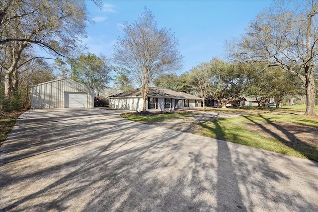 view of front of house featuring an outbuilding, a detached garage, a front yard, and driveway