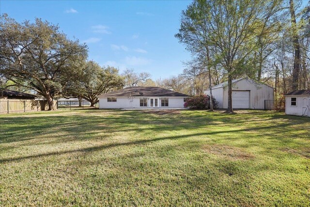 view of yard featuring a detached garage, an outbuilding, and fence