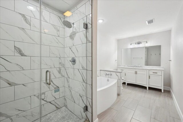 full bath with vanity, baseboards, visible vents, a tub, and a stall shower