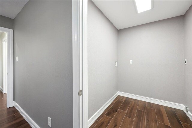 corridor featuring baseboards and dark wood-style floors