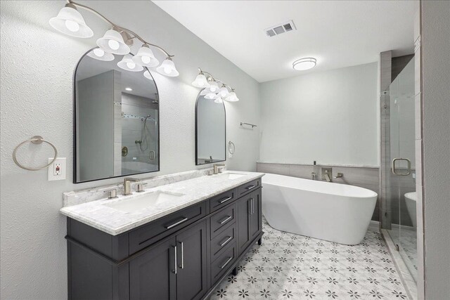 bathroom featuring double vanity, a stall shower, visible vents, and a sink