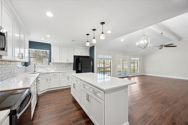 kitchen featuring wood finish floors, lofted ceiling with beams, a sink, black appliances, and tasteful backsplash