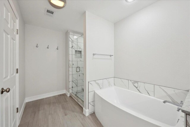 full bath featuring wood finished floors, baseboards, visible vents, a stall shower, and a garden tub