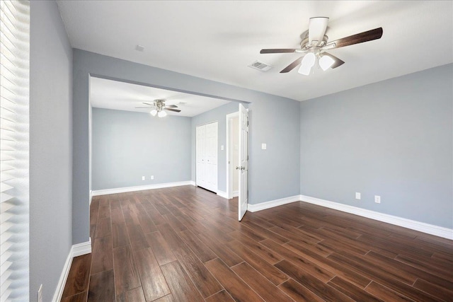 unfurnished room with visible vents, baseboards, dark wood-type flooring, and ceiling fan