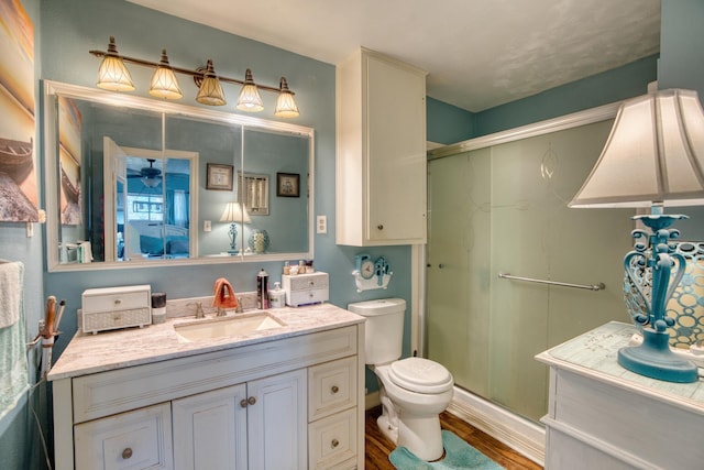 bathroom featuring hardwood / wood-style flooring, vanity, toilet, and a shower with door