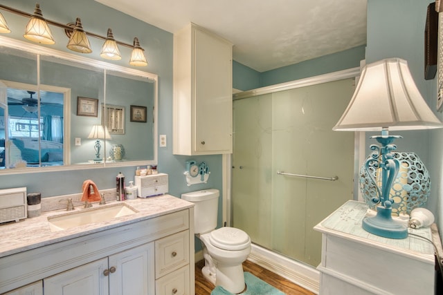 bathroom featuring hardwood / wood-style flooring, vanity, toilet, and a shower with door