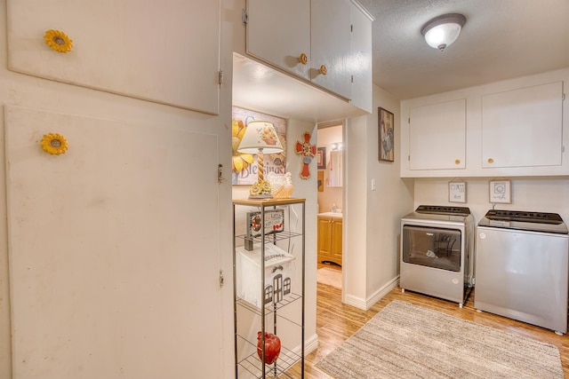 laundry room featuring cabinets, a textured ceiling, washing machine and clothes dryer, and light hardwood / wood-style floors