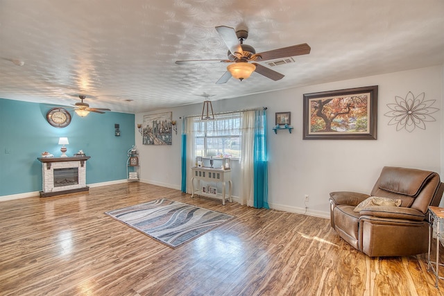 sitting room featuring hardwood / wood-style flooring, ceiling fan, and a fireplace