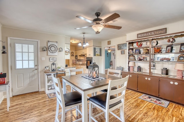 dining area with ceiling fan with notable chandelier and light wood-type flooring