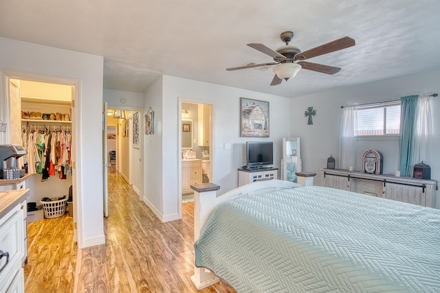 bedroom featuring ceiling fan, connected bathroom, light hardwood / wood-style floors, a spacious closet, and a closet