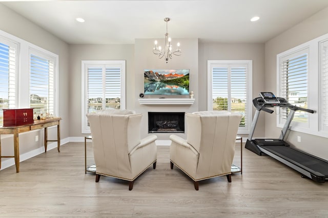 living area with plenty of natural light, light hardwood / wood-style flooring, and an inviting chandelier