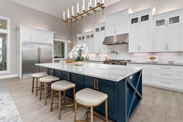 kitchen with a breakfast bar, a center island, white cabinets, hanging light fixtures, and stainless steel appliances