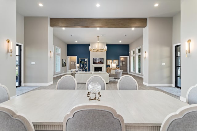 dining room with beam ceiling, light hardwood / wood-style floors, and an inviting chandelier