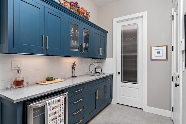 bar with decorative backsplash, sink, blue cabinetry, wine cooler, and light tile patterned flooring