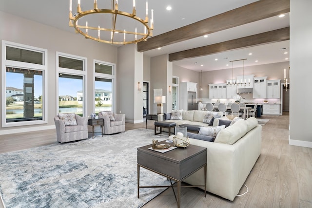 living room with a towering ceiling, light hardwood / wood-style flooring, beamed ceiling, and a notable chandelier