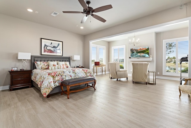 bedroom featuring multiple windows, light hardwood / wood-style flooring, and ceiling fan with notable chandelier