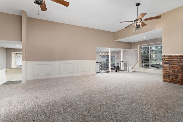 unfurnished living room featuring ceiling fan with notable chandelier and carpet floors