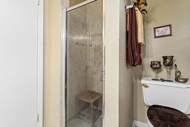 bathroom featuring toilet and a shower with shower door