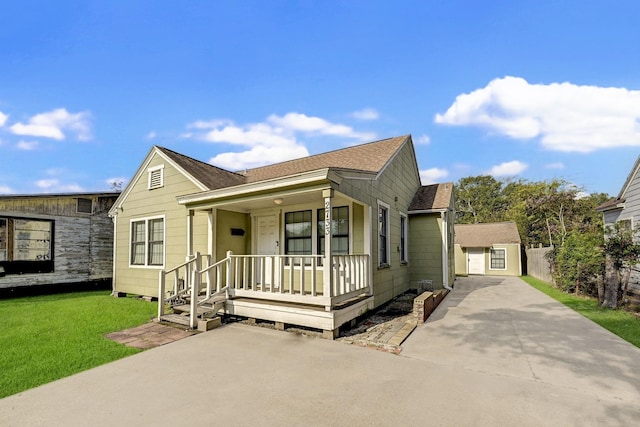 view of front facade with a porch, a garage, an outdoor structure, and a front lawn