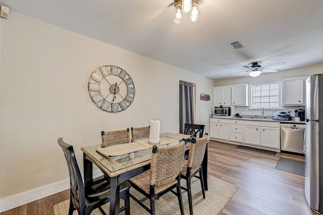 dining room with hardwood / wood-style floors, ceiling fan, and sink