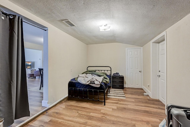 bedroom featuring a textured ceiling, lofted ceiling, and hardwood / wood-style flooring