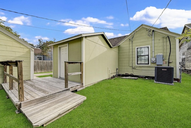 back of house featuring a lawn, a deck, central air condition unit, and a shed