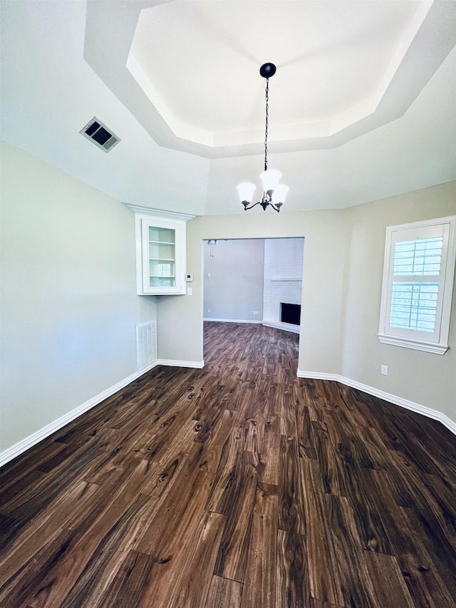 2411 Post Oak Ln, Groves, TX 77619 - unfurnished room featuring a raised ceiling, a chandelier, and dark wood-type flooring